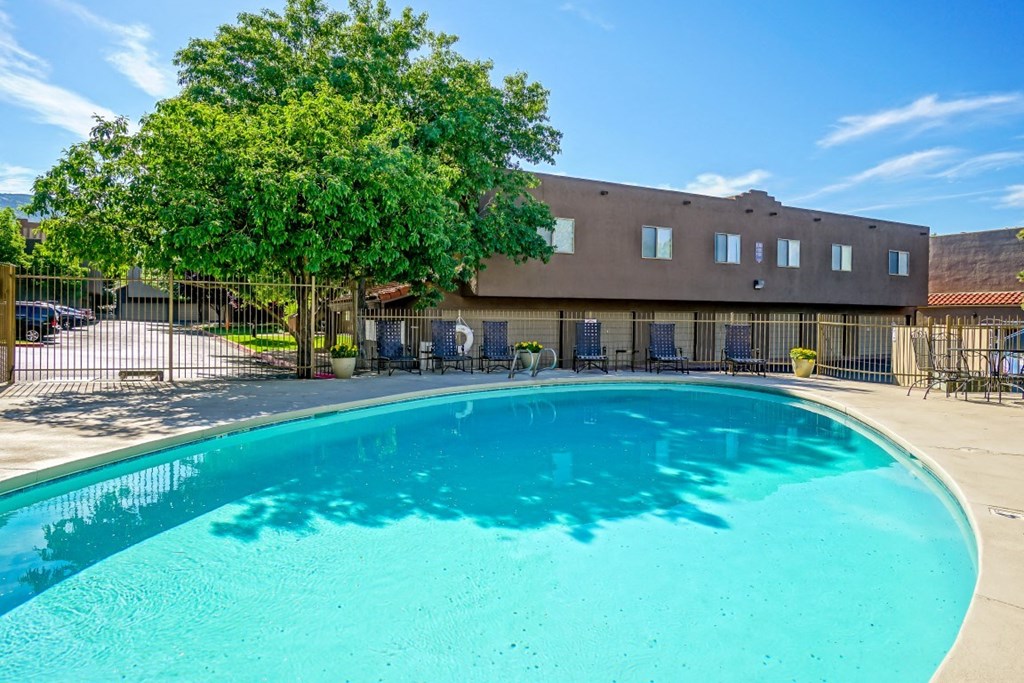 A large swimming pool in front of a building with a fence around it.